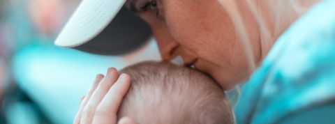 Maman solo mais multi galères Une maman de profil embrasse le crâne de son bébé, regard dans le vague