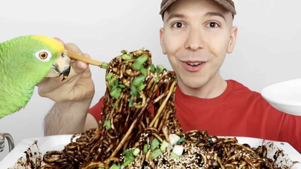 Un ehomme en tshirt rouge mange des pates