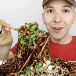 Un ehomme en tshirt rouge mange des pates