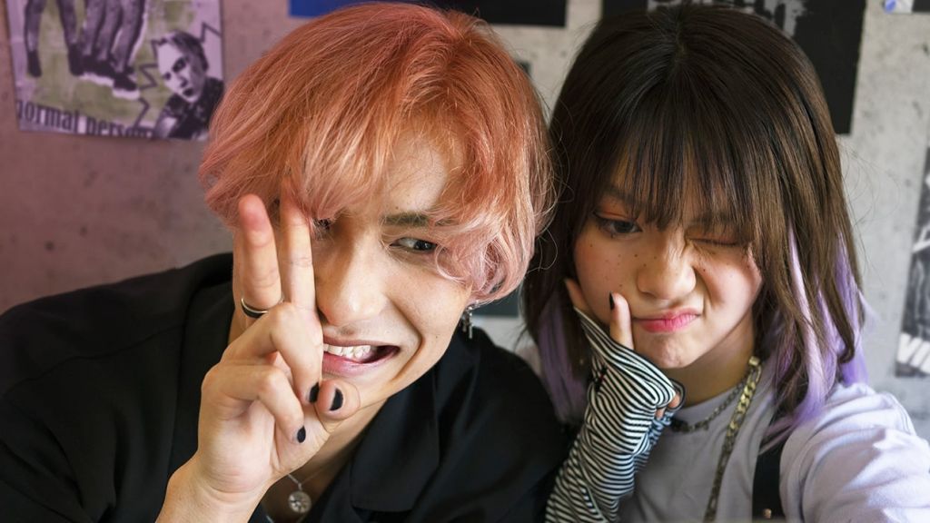 Un jeune homme cheveux orange et une jeune fille brune, tous deux asiatiques font des grimaces