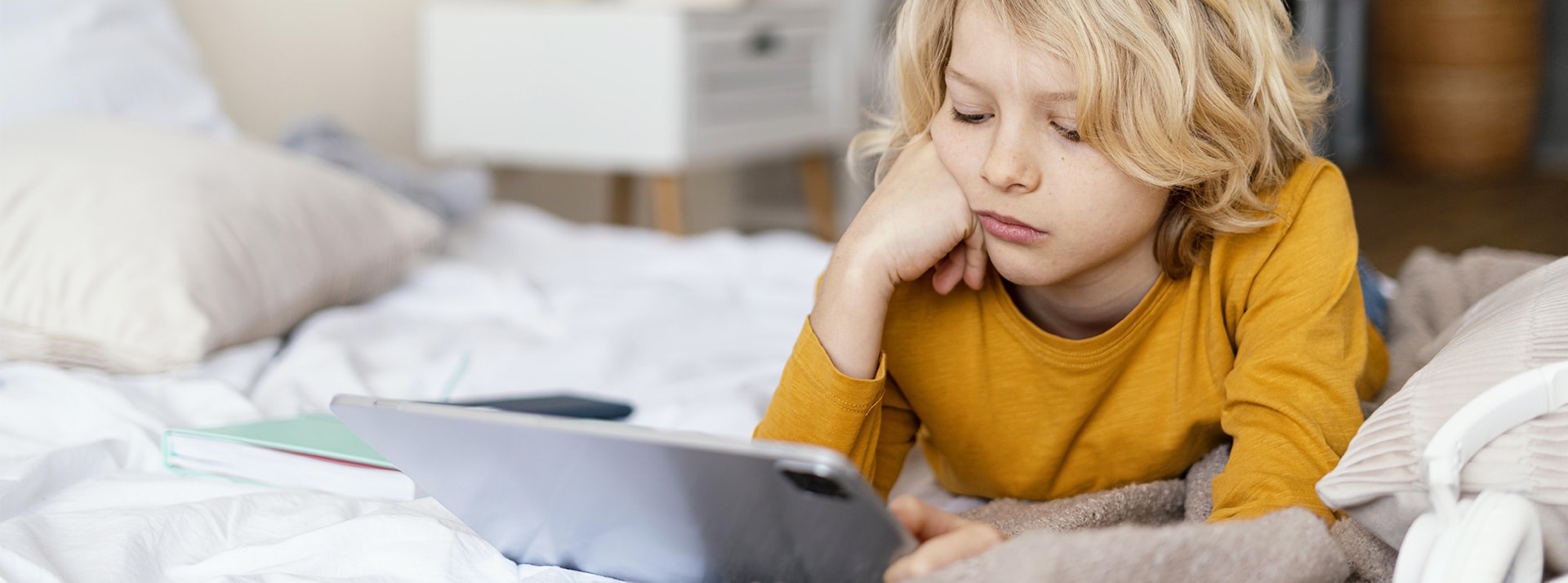 pad Kids : la génération Alpha est sur X et ça craint - L'ADN Un jeune garçon blond sur son lit avec un Ipad