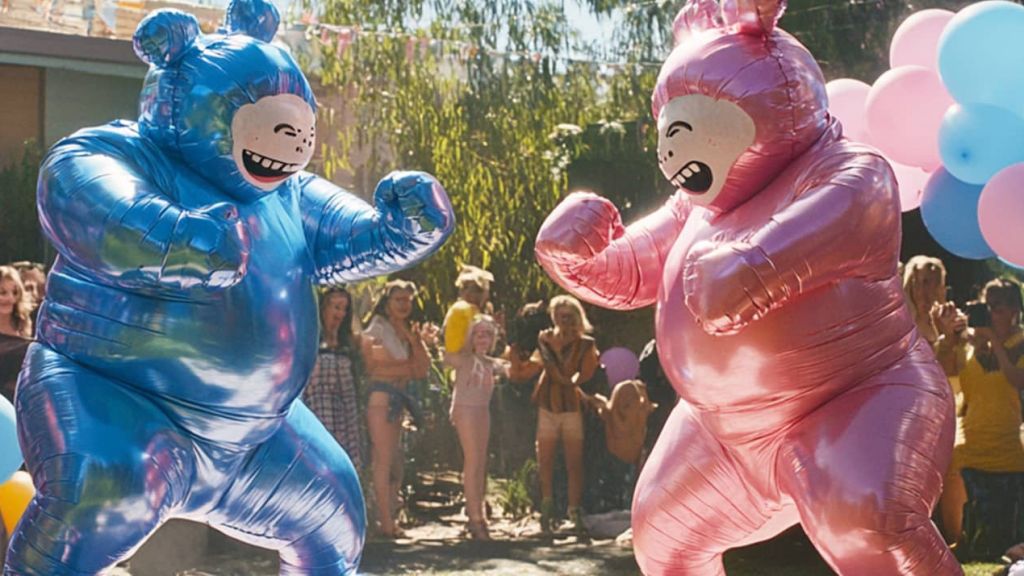 Gender reveal party Deux personnes déguisées en bébé bleu et rose boxent dans un jardin