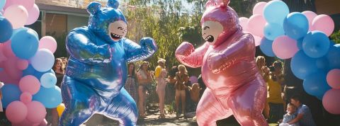 Gender reveal party Deux personnes déguisées en bébé bleu et rose boxent dans un jardin