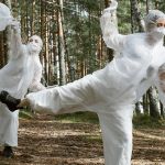 3 personnes en forêt dansent en combinaisons blanches en ramassant des déchets