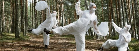 Écologie : l'heure du backlash 3 personnes en forêt dansent en combinaisons blanches en ramassant des déchets