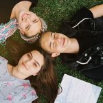 Des adolescents joyeux allongés sur l'herbe avec leurs cahiers ouverts