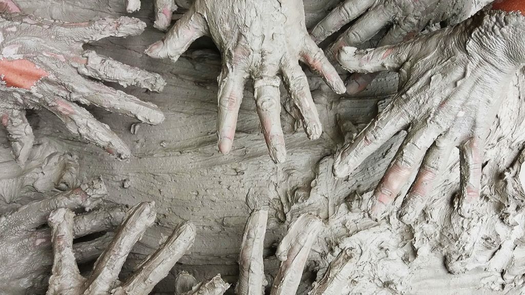Plusieurs paires de mains pleines d'argile en contact d'argile