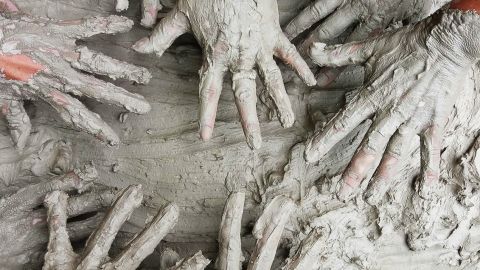 Plusieurs paires de mains pleines d'argile en contact d'argile