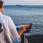 Un jeune homme de dos peint la mer