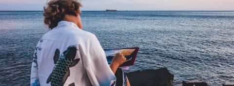 Un jeune homme de dos peint la mer