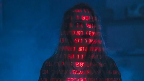 femme sur fond foncé avec écritures numériques sur le visage