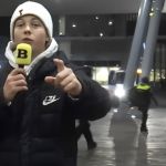 une jeune garçon au bonnet blanc devant un stade