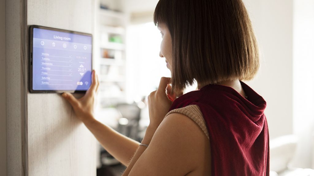 femme régulant la température de son appartement avec un appareil connecté