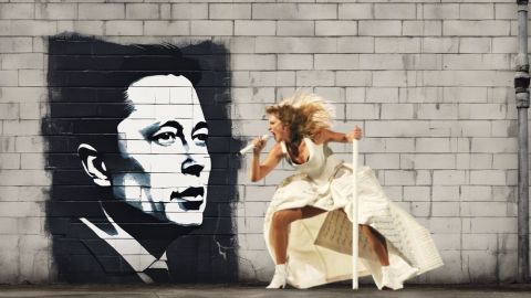 Taylor qui hurle contre un mur en briques sur un pochoir d'Elon Musk