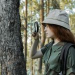 Une jeune fille inspecte le tronc d'un arbre dans une forêt