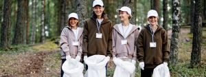 4 jeunes étudiantes en forêt avec des sacs pour ramasser les déchets