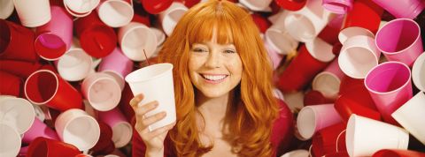 Gobelets jetables, vitrines et déodorants : la longue histoire du consumérisme Une jolie femme rousse entourée de gobelets en plastique de couleurs