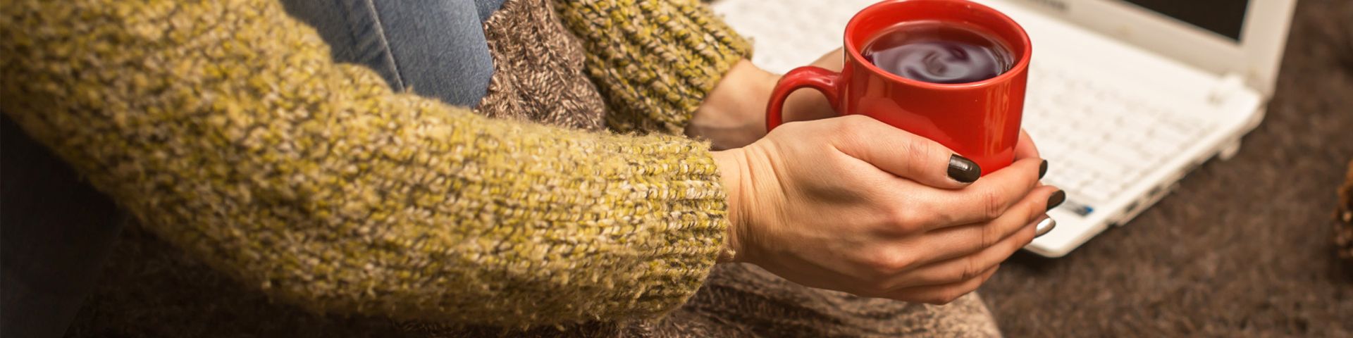 Une femme avec gros pulle et grosses chaussettes tient un mug de thé brûlant pour se réchauffer
