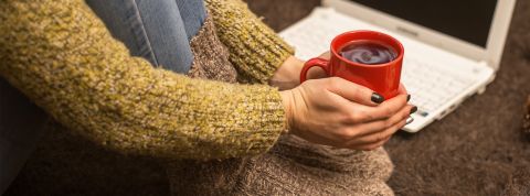 Précarité énergétique : 30 ans d'action contre l'exclusion Une femme avec gros pulle et grosses chaussettes tient un mug de thé brûlant pour se réchauffer