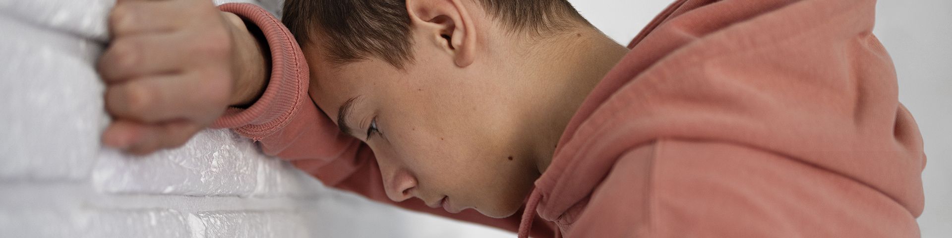 Un jeune garçon tête contre le mur, super déprimé