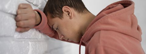 Converser avec des IA est-il dangereux ? Un jeune garçon tête contre le mur, super déprimé