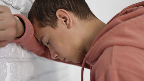 Un jeune garçon tête contre le mur, super déprimé