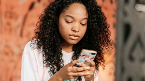 Les psys sur les réseaux : Des influenceurs qui vous veulent du bien ? Une jeune metisse sur son smartphone