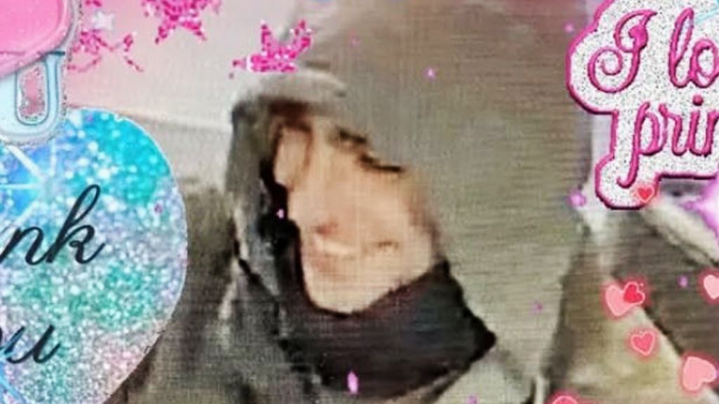 un homme en capuche entouré d'inscriptions roses