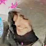 un homme en capuche entouré d'inscriptions roses