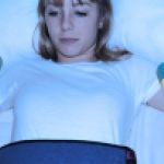 Une jeune femme contrainte sur un lit et des gélules qui tombent sur elle