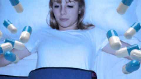 Une jeune femme contrainte sur un lit et des gélules qui tombent sur elle