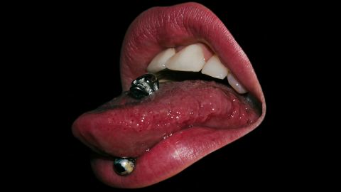 Une bouche sur fond noir ave piercing dans la langue