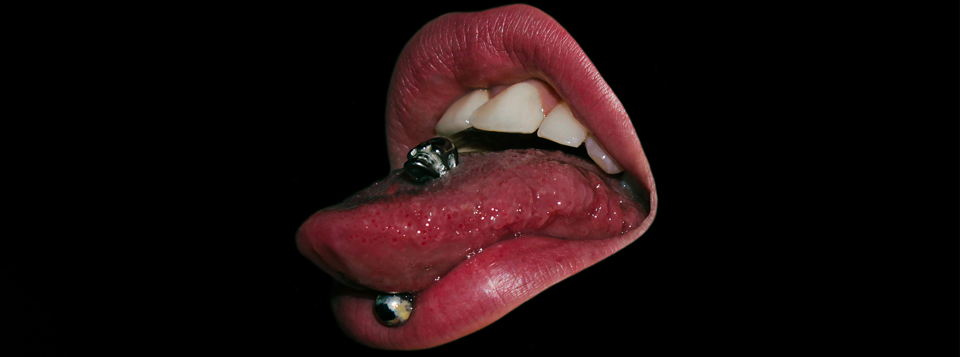 Entre recherche de « réel » et plongé dans la fantaisie pop, que disent de nous les tendances de recherche de Pornhub ? - L'ADN Une bouche sur fond noir ave piercing dans la langue