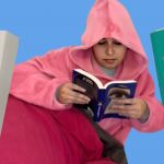 Une jeune fille lovée dans un sweat à capuche lit un livre