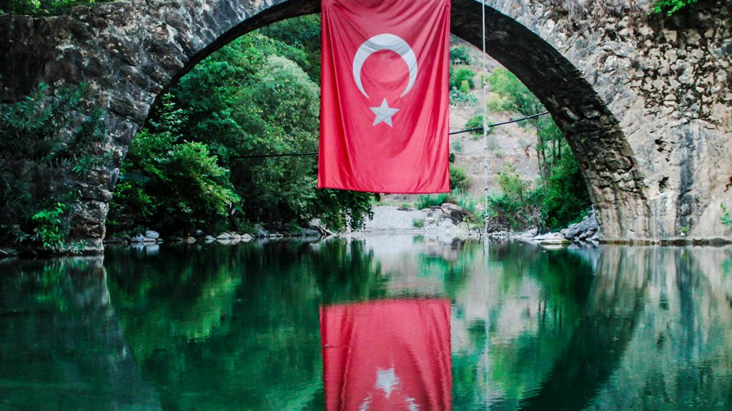 Un drapeau turx sur un pont se reflète dans l'eau