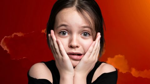 Une petite fille inquiète sur un fond de ciel rouge