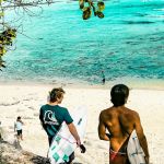 Deux surfers et plusierus personnes sur une plage balinaise