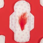 Des serviettes hyginéiques blanches et la centrale avec une plume rouge