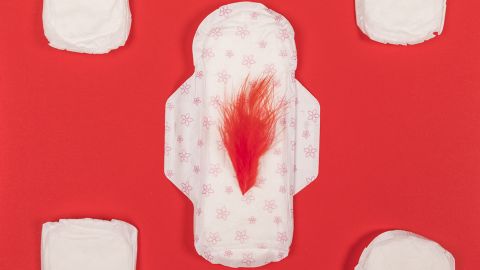 Des serviettes hyginéiques blanches et la centrale avec une plume rouge