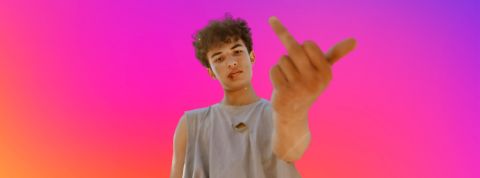 I F**K Insta ! Ces tendances visuelles qui prennent l'esthétique des réseaux à contre-pied Un jeune homme qui fait le signe fuck sur fond aux couleurs Instagram
