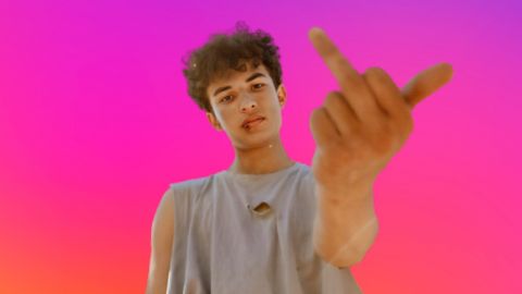Un jeune homme qui fait le signe fuck sur fond aux couleurs Instagram