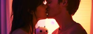 Un couple s'embrasse tandis qu'un petit robot les regarde