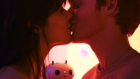 Un couple s'embrasse tandis qu'un petit robot les regarde