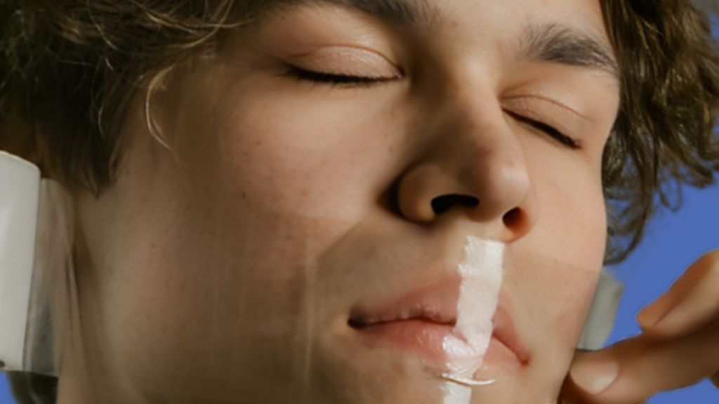Un homme, les yeux fermés, qui se scotche la bouche