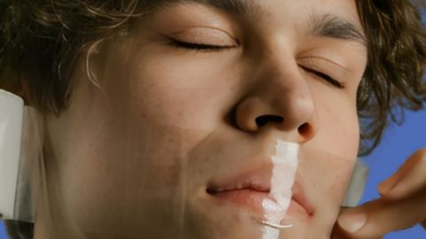 Un homme, les yeux fermés, qui se scotche la bouche