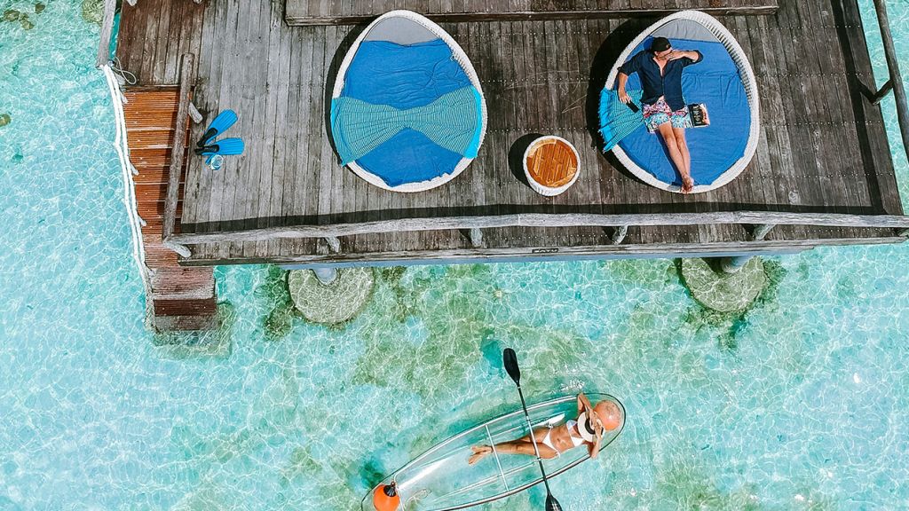 Vue aérienne d'une maison sur l'eau turquoise avec un couple