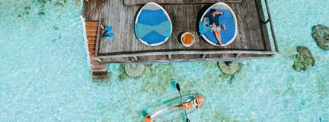 Tourisme : les Français séduits par le voyage adult only Vue aérienne d'une maison sur l'eau turquoise avec un couple