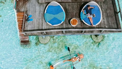 Vue aérienne d'une maison sur l'eau turquoise avec un couple