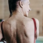 Une senior de dos au bord d'une piscine d'un immeuble de luxe