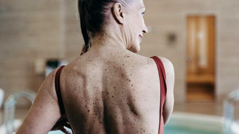 Une senior de dos au bord d'une piscine d'un immeuble de luxe